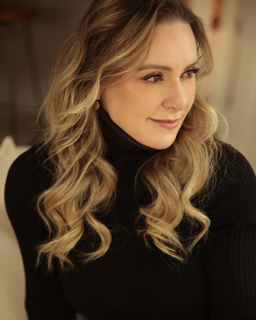 Patrícia Sivieri de blusa preta de gola alta, olhando para o lado
